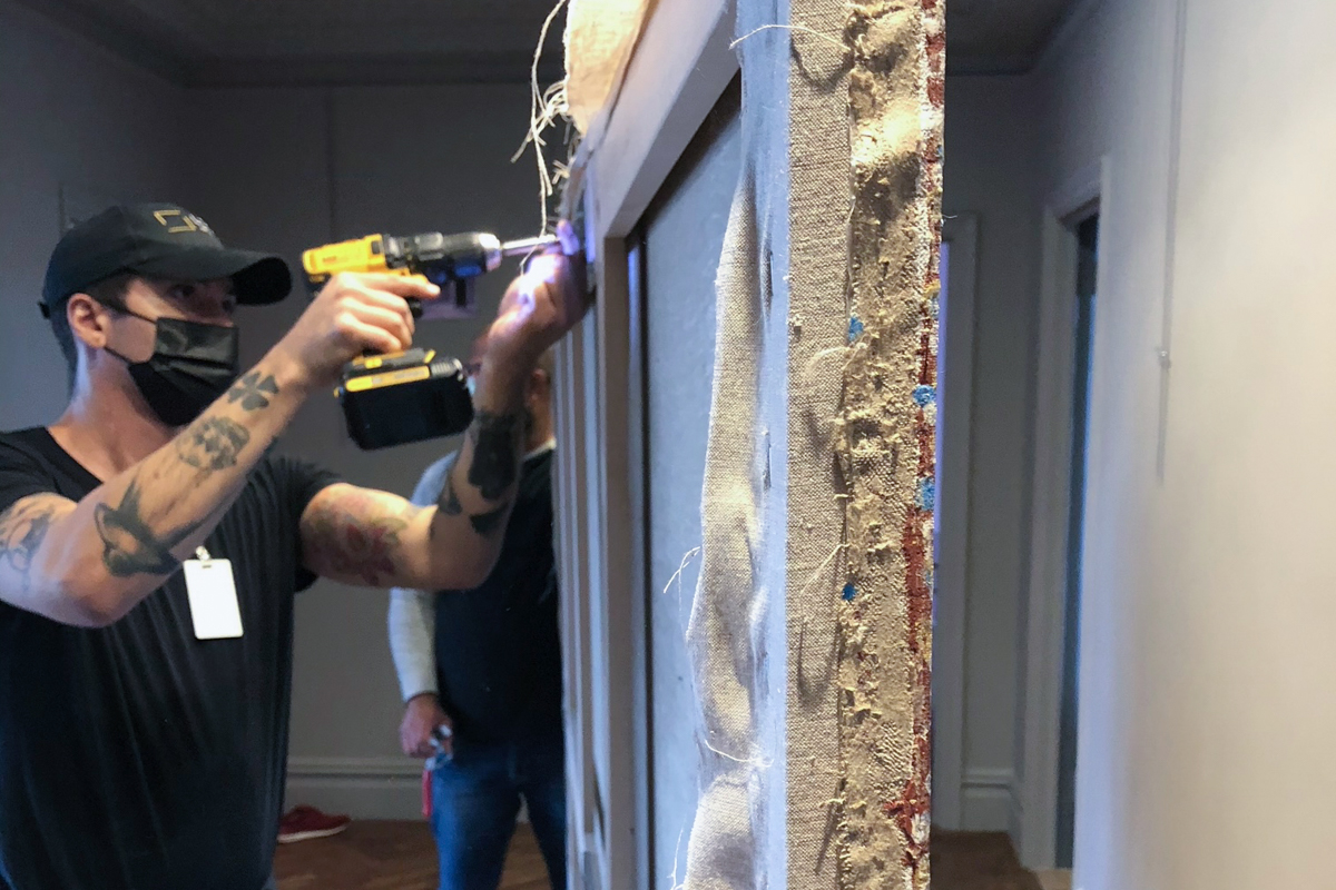 Lowy Prepares a Painting by Bill Whiskey Tjapaltjarri For Installation